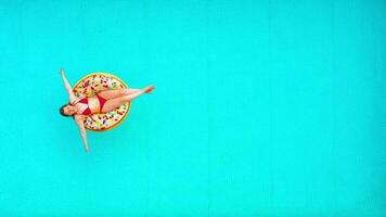 Aerial view of a woman in red bikini swimming on a donut in the pool video