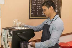 un barista está parado en su cafetería. parece orgulloso de su profesión. foto