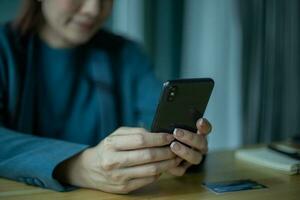 Senior asian woman using smartphone while sitting at home office. photo