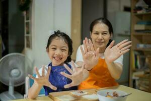 asiático madre y hija son Cocinando comida y teniendo divertido en el cocina. foto