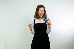 asiático mujer en delantal posando participación crédito tarjeta. foto