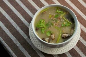 top view rice porridge with minced pork and shiitake mushrooms in a ceramic cup on a plate on brown and white fabric background, food, health, vegetable, copy space photo