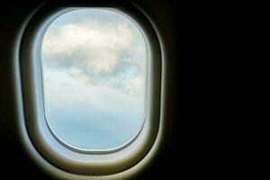 Closeup window in the airplane with view of blue sky and white cloud background. photo