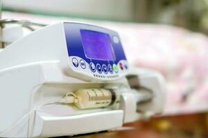 Syringe pump machine with monitor display pumping milk to sick newborn baby  at NUCU ward in the hospital. photo