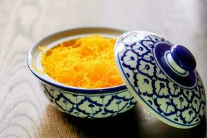 Thai traditional sweet and dessert in beautiful Thai design white ceramic bowl on wooden table and blurry background with nature sunlights. photo