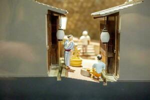 Closeup half cut of 1800's Ancient Japanese house in miniature models and Japanese people in daily life. Osaka prefecture, Japan. photo