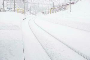 paisaje urbano ver y de cerca metal largo ferrocarril pista en invierno temporada y nieve tapado ciudad con completamente blanco brumoso desde nieve tormenta antecedentes. foto