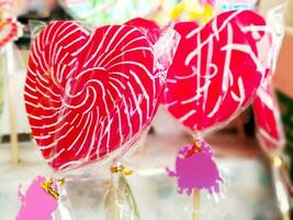 Closeup and crops colorful sweet lollypops with labels for sale on wooden shelf background. photo