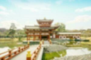 Scenic view and blurred of Byodoin Japanese buddhist temple with bridge on bright blue sky background. photo