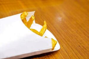 Top view and crop of french fries in white box and on wooden table. photo