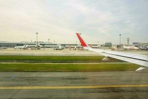 Bangkok, Thailand 11 2018- Outside view of airplane on the airport runway while the plane is prepared to take off with blue sky and many air plane and the terminal building background. photo