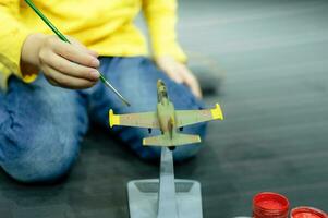 kid boy painting aircraft model photo