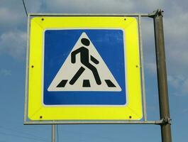 Blue, white and yellow pedestrian crossing sign on the sky background photo