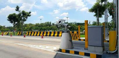 Group of CCTV camera installed for recording accident on road or street with painted yellow and black barrier, tree and sky background. Protection, Observe traffic photo