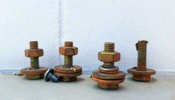 Group of nuts and bolts put on floor with wall background. Rusty and use tools for fixing machines, engines or industry. photo