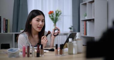 Beautiful young Asian woman blogger shows how to make up cosmetics at home photo