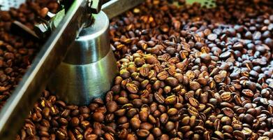 Freshly roasted aromatic coffee beans over a modern coffee roasting machine. photo