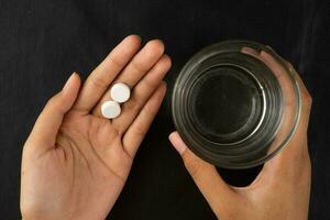 hand holding medicine pill and glass of water photo