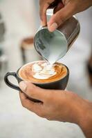 primer plano abstracto de la cafetería, taza de café latte art. barista haciendo una taza de café latte art. tono vintage de algunas personas vierten leche para hacer café con leche foto