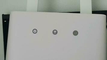 The wifi indicator of a modem is on. The modem router is white. video