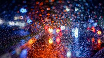 Raindrops on a car windscreen with colorful traffic background at night in Cibinong, West Java, Indonesia photo