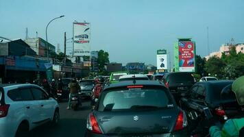 Bogor, West Java, Indonesia, May 2 2023 - Very heavy traffic of cars and motorcycle at one of the intersections of Bogor city during a sunny day. photo