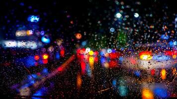 Raindrops on a car windscreen with colorful traffic background at night in Cibinong, West Java, Indonesia photo