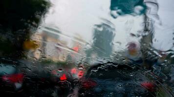 gotas de lluvia en el parabrisas de un coche conducción a lo largo el calle en un soleado tarde foto