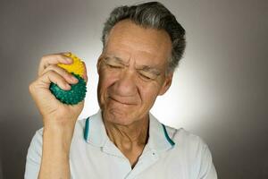 Mature man holding and squeezing massage therapy spike balls photo
