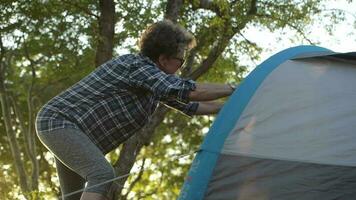 Summer Vacation in a Tent. Retired Caucasian Woman in Her 60s Preparing Her Tent Checking Material Tension. video