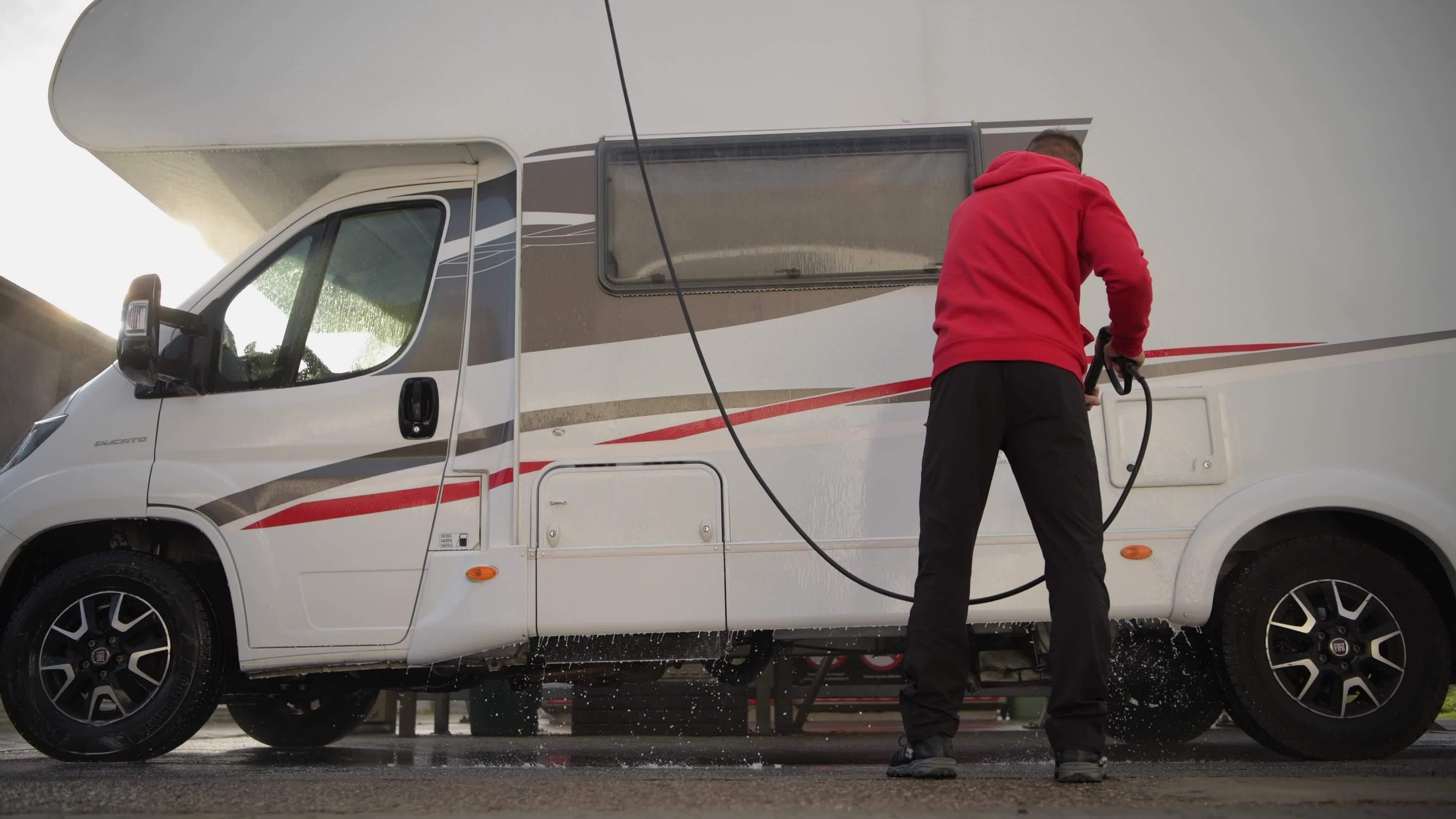 RV Camper Pressure Washing. Caucasian Motorhome Owner Cleaning His