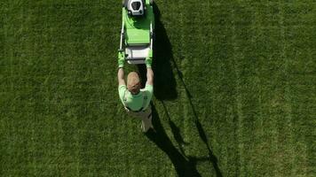 caucasico giardiniere con benzina erba falciatore a opera. paesaggio attività commerciale. industriale tema. prato in movimento aereo filmato. video