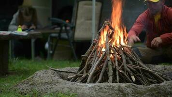 uomini ardente campo fuoco. il suo figlia disegno qualcosa su un' tavolo nel davanti di loro camper furgone camper. campeggio volta. video