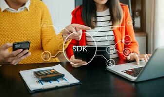 SDK  Software development kit programming language technology concept, Person typing laptop computer and tablet with SDK icon on virtual screen. in office photo