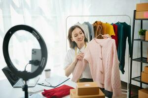 Beautiful lady blogger showing clothes in front of the camera to recording vlog video live streaming photo