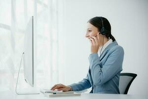 Serious call center operator in wireless headset talking with customer, woman in headphones with microphone consulting client on phone in customer support service in business center photo