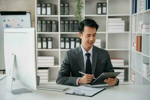 Young business man working at office with laptop, tablet and taking notes on the paper. photo