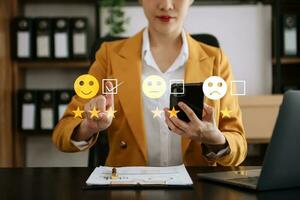 Customer service evaluation concept. Businesswoman pressing face smile emoticon show on virtual screen at tablet and smartphone photo