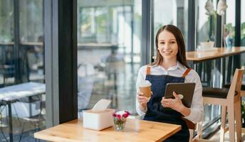 dueña de una cafetería con bloc de notas y tableta digital lista para recibir pedidos. en cafetería restaurante. mujer barista café foto