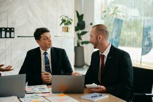 Two business workers talking on the smartphone and using laptop at the office. photo