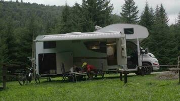 estate tempo famiglia ricreazione. caucasico padre e il suo figlia a il tavolo nel davanti di loro camper rv camper. video