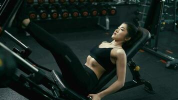 Jeune femme dans tenue de sport travail sa Faire exercice quads à machine presse dans le salle de sport. video