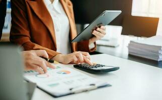 Business documents on office table with smart phone and calculator digital tablet and graph business with social network diagram and two colleagues discussing data working in the office photo