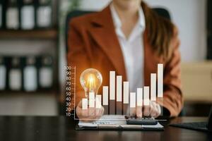 Businesswoman holding and putting lightbulb on coins stack on table for saving energy and money conceptIdea saving energy photo