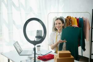 Beautiful lady blogger showing clothes in front of the camera to recording vlog video live streaming photo