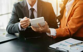 Business documents on office table with smart phone and calculator digital tablet and graph business with social network diagram and two colleagues discussing data working photo