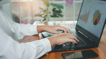 Businesswoman using laptop computer on wooden table And she is looking at the graph displayed on the computer screen. business concept photo