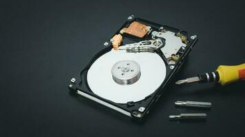 Memory repair concept. Repair of storage systems. Hard disk repair. Hard disk with screwdriver on dark background photo