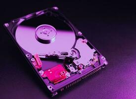 An open hard disk disassembled HDD of a computer or laptop lies on a purple surface. Computer hardware and accessories. Hard disk storage. photo