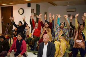 New Delhi, India, May 31 2023 - Group Yoga exercise class for people of different age in Yoga institute, International Yoga Day, Big group of adults attending a yoga class at yoga art of living centre photo